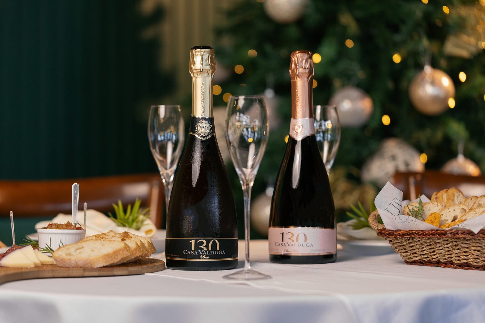 Espumantes Casa Valduga 130 Brut e Rosé com taças à mesa, diante de uma árvore iluminada