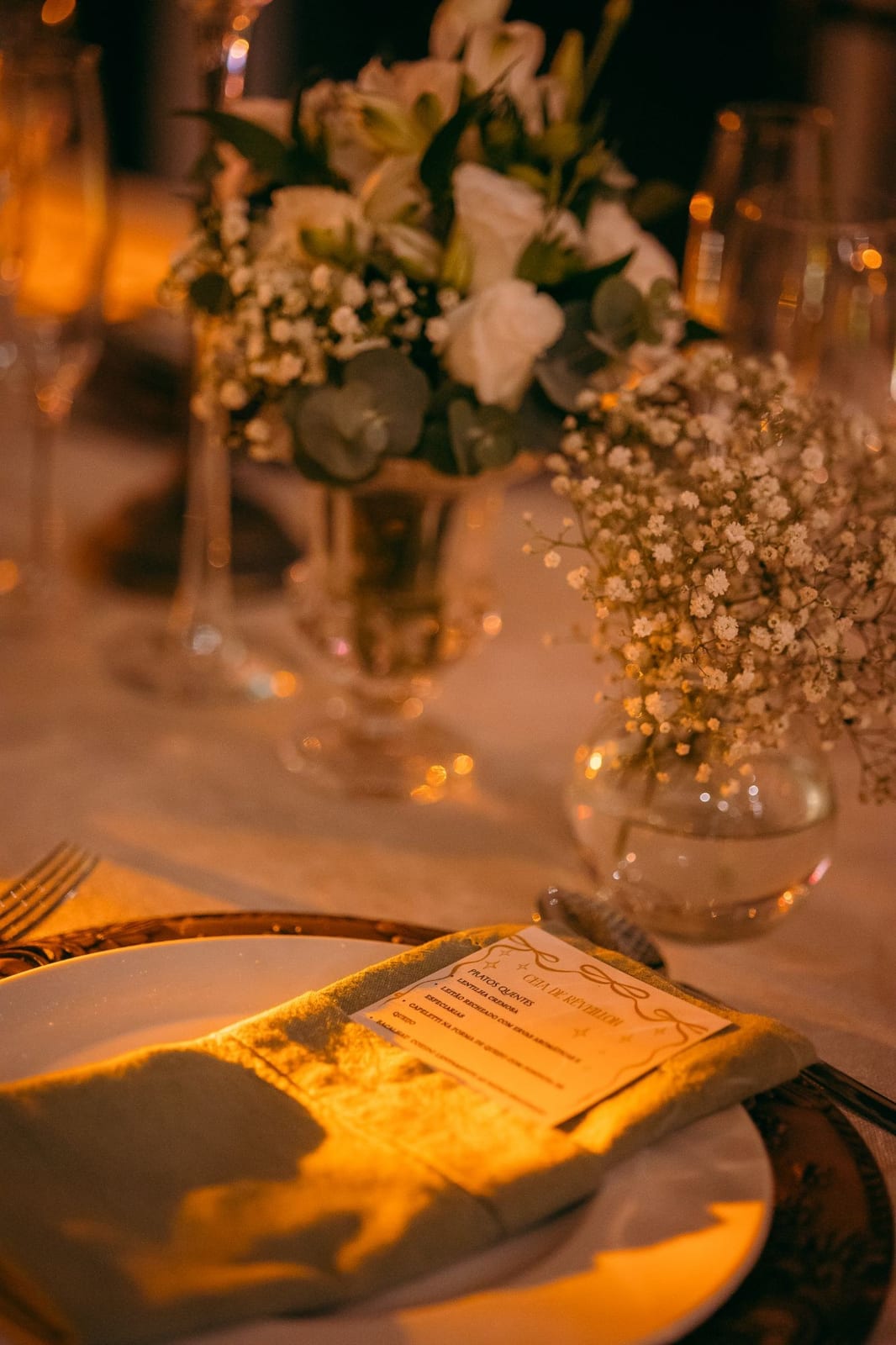 Mesa posta com o cardápio da Ceia de Réveillon e arranjo de flores brancas